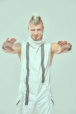 Kollarını kaplayan dövmeleri olan havalı sarışın punk rock müzisyeninin portresi. Stüdyonun arka planında kameraya bakıyor. Siber punk stili. 