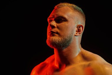 Siyah arka planda kırmızı ışıkla poz veren güçlü kızıl saçlı atletik bir adamın portresini yakından çek. Erkek güzellik konsepti.