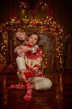Noel arifesini şöminenin yanında geçiren örgü kazaklı güzel bir anne ve sevgili kızının portresi. Mutlu Noeller aile.. 