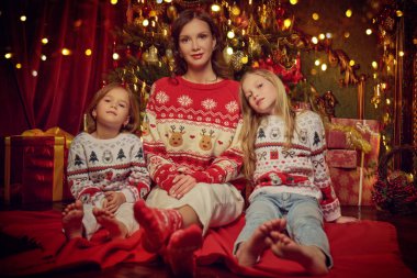 Güzel anne ve sevgili kızları Noel arifesinde Noel arifesini rahat bir aile ortamında Noel ağacının yanında oturarak geçiriyorlar. Mutlu Noeller. Tam boy çekim. 