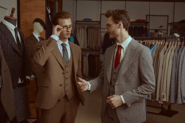 Saygıdeğer klasik takım elbiseli ve gözlüklü iki başarılı iş adamı prim erkek giyim mağazasında iş konuşuyorlar. İş stili, moda.