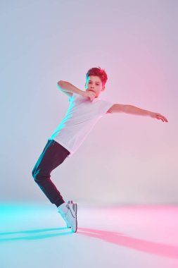 Çağdaş danslar. Profesyonel hip hop ve break dansçı çocuk stüdyoda beyaz arka planda karışık renkli ışıkta dans ediyor. Tam boy portre. 