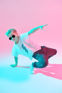 Modern dans stili. Stüdyoda dans eden havalı break dansçı çocuk beyaz arka planda karışık renkli ışıkta dans ediyor. Hip-hop dansçısı. Spor ve aktiviteler.