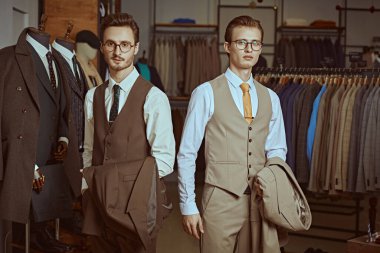 Zarif klasik takım elbiseli ve gözlüklü iki saygıdeğer adam prim erkek giyim mağazasında yan yana durur. İş stili. Erkek modası. 