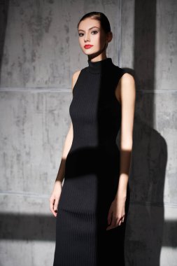 Gece makyajlı zarif bir kızın portresi. Grunge arka planda siyah örülü bir beden giysisi ile poz veriyor. Moda fotoğrafı. Işık ve gölgeler.