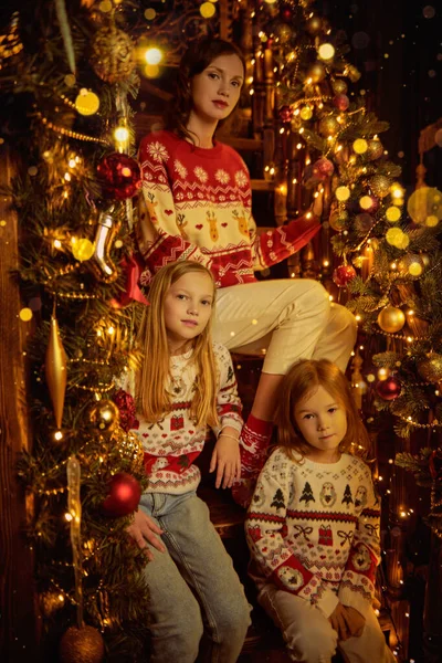 Güzel anne ve tatlı kızları Noel akşamını sıcak bir aile ortamında ışıldayan ışıkların arasında neşeli bir şekilde dekore edilmiş bir merdivende oturarak geçirirler. Mutlu Noeller aile.. 
