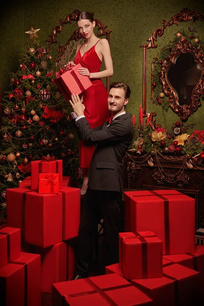 Noel ve Yeni Yıl kutlaması. Zarif bir gece elbisesi içindeki yakışıklı bir adam hediye kutularının üzerinde duran güzel kız arkadaşına hediye verir. Noel için lüks bir yer. Tatil modası. 