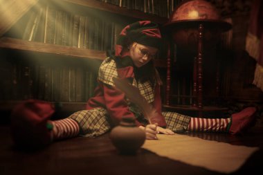 Ciddi, küçük bir elf kızı eski bir kütüphanenin yanında oturuyor ve Noel kutlamasına hazırlanmak için uzun bir liste hazırlıyor. Tam yol ileri. Noel masalları. 