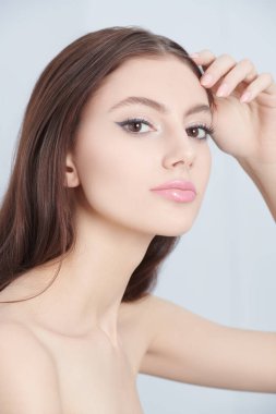 Cosmetics and skin care. A beautiful slender brunette girl with elegant makeup poses on a white background at studio. Women's beauty and health. 