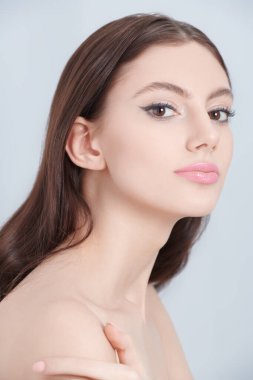 Cosmetics and skin care. A beautiful slender brunette girl with elegant makeup poses on a white background at studio. Women's beauty and health. 