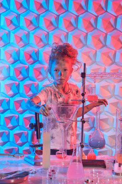 Portrait of a cute little girl with matted hair and the consequences of a chemical explosion on a white t-shirt, face and hands after scientific experiments. Education. Chemical experiments for children.