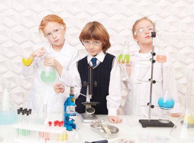 Three inquisitive children scientists are conducting chemical experiments in the laboratory. Educational concept. Discovery. clipart