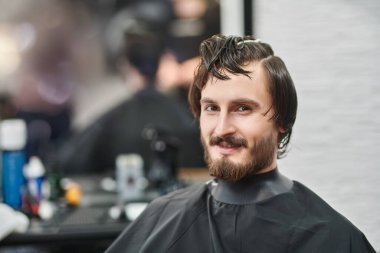 Sakallı ve bıyıklı neşeli, yakışıklı esmer adam kuaför salonundaki kuaförünü ziyaret ediyor. Berber dükkanındaki mutlu müşteri.. 