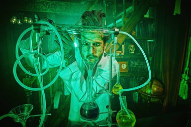 Laboratuvarında deneyler yapan çılgın bir bilim adamı gizemli bir yeşil ışıkla aydınlatılıyor. Bir bilim kurgu romanının karakteri. 