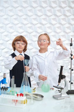 Keşif. Laboratuvarda kimyasal deneyler yapan iki çocuk bilim adamı. Eğitici bir kavram. Çocukların erken gelişimi.