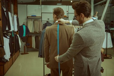 Başarılı genç işadamı, kaliteli erkek giyim mağazasında terzilik hizmeti alıyor. Erkeklerin iş modası. 