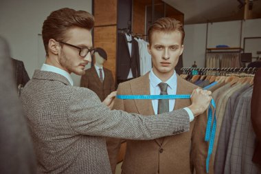 Başarılı genç işadamı, kaliteli erkek giyim mağazasında terzilik hizmeti alıyor. Erkeklerin iş modası. 