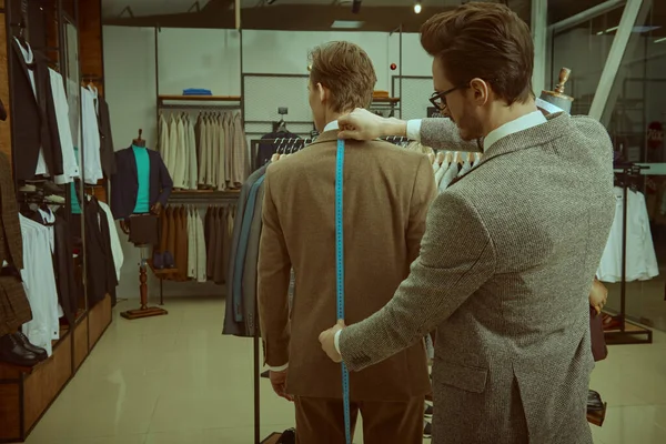 Başarılı genç işadamı, kaliteli erkek giyim mağazasında terzilik hizmeti alıyor. Erkeklerin iş modası. 