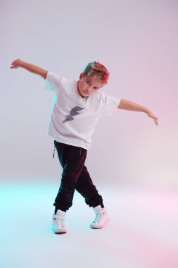 Modern dans stili. Stüdyoda dans eden havalı break dansçı çocuk beyaz arka planda karışık renkli ışıkta dans ediyor. Hip-hop dansçısı. Spor ve aktiviteler.