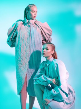 Güzellik ve moda konsepti. Beyaz bir arka planda parlak sarı elbiseli sarı okları olan güzel sarışın bir mankenin portresi. Makyaj ve kozmetik.