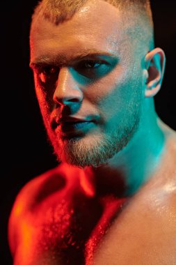 Güçlü ve kendine güvenen bir haltercinin portresi. Siyah arka planda duran çıplak bir halterci. Kırmızı ışıklı. Profesyonel spor, şampiyon.. 