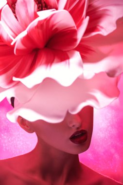 Parfüm, makyaj ve kozmetik. Güzel, zarif, esmer bir kızın sanatsal portresi kafasında büyük, narin bir şakayık çiçeğiyle yüzünü gizliyor.. 