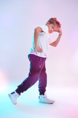 Modern dans stili. Stüdyoda dans eden havalı break dansçı çocuk beyaz arka planda karışık renkli ışıkta dans ediyor. Hip-hop dansçısı. Spor ve aktiviteler.