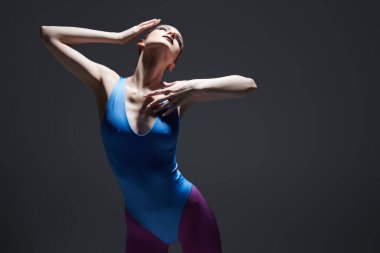 Koyu gri bir arka planda sahne ışıkları altında balerin gibi poz veren etkileyici manken kız. Sanat ve moda. Boşluğu kopyala.