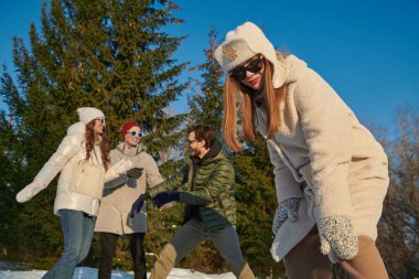 Kış aktiviteleri. Neşeli kız ve erkek arkadaşlarının portresi güneşli bir günde kış parkında dinleniyor ve seviniyor. Kış modası. İyi ruh hali, duygular. 