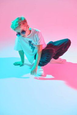 Hip-hop dansçısı. Stüdyoda dans eden havalı break dansçı çocuk karışık renkli ışıkta pembe arka planda dans ediyor. Spor ve aktiviteler. Modern dans stili. 