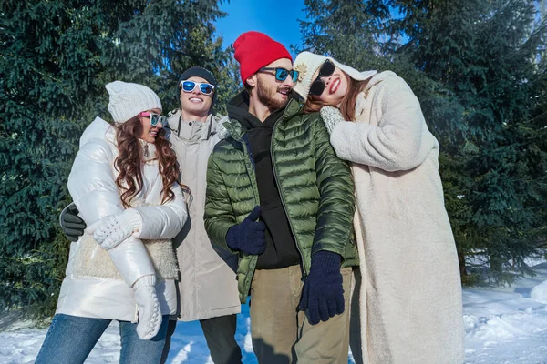 Kış aktiviteleri. Neşeli kız ve erkek arkadaşlarının portresi güneşli bir günde kış parkında dinleniyor ve seviniyor. Kış modası. İyi ruh hali, duygular. 