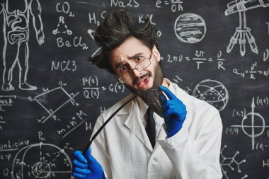 Eğitim ve bilim. Komik, zeki bir profesör elinde bir kalemle karatahtanın önünde duruyor ve temel bilim bilgisini açıklamaya çalışıyor.. 