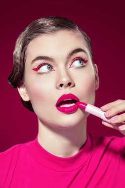 Güzellik kızı. Parlak pembe renk. Parlak makyajlı güzel bir kız modelin portresi. Burgundy arka planda harika pembe bir ruj sürüyor. Yakın çekim..