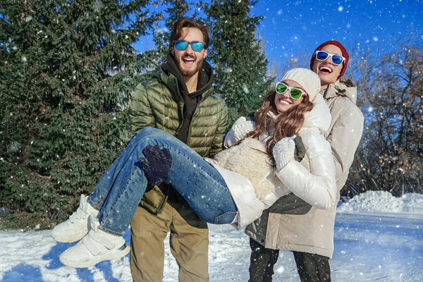 Kış parkında hareketlilik. Neşeli gülen arkadaşlar erkekler ve bir kız kış parkında kar altında eğleniyorlar. Kış modası. İyi ruh hali, duygular. 