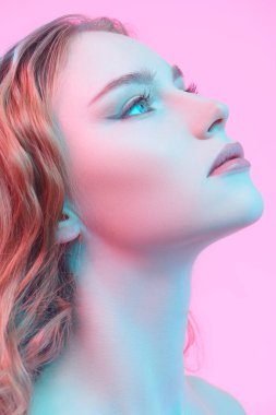 Stüdyoda pembe arka planda poz veren açık renk makyajlı güzel kızıl saçlı bir kızın portresi. Kadın güzelliği ve sağlığı. Kozmetik ve cilt bakımı. 