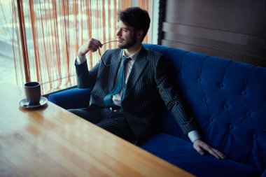 Zarif takım elbiseli yakışıklı esmer iş adamı bir restoranda öğle yemeği yiyor.. 