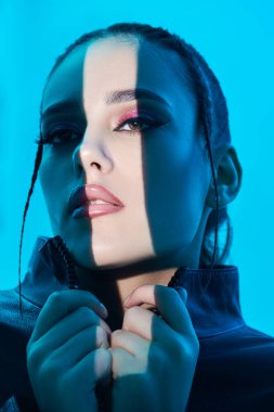 Güzellik, makyaj ve makyaj konsepti. Parlak akşam makyajı ve yüzünde parlak bir ışık demeti olan güzel esmer bir kızın portresi. Mavi arka plan. Stüdyo çekimi. 