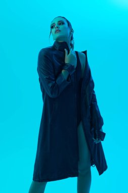 Çekici bir esmer modelin stüdyo portresi açık mavi arka planda şık bir siyah deri ceketle poz veriyor. Moda fotoğrafı.. 