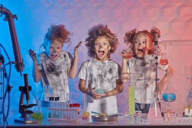 Saçları tomurcuklanmış bir grup komik çocuk başarısız bir deneyden sonra kimya laboratuvarında çığlık çığlığa bağırıyor. Bilim deneyleri ve çocuklar. 