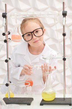 Şirin gülümseyen küçük bir kız laboratuarda deneyler yapıyor. Bilim ve eğitim.