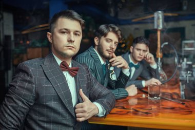 Şık, klasik takım elbiseli yakışıklı genç erkekler bir barda rahatlar. Erkek modası. İş adamları kulübü.