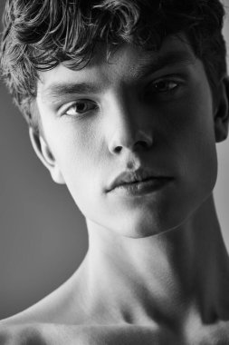 Üstsüz poz veren yakışıklı bir gencin stüdyo portresi. Siyah ve beyaz atış. Erkek güzelliği ve sağlığı. 