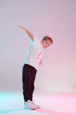 Modern dans stili. Stüdyoda dans eden havalı break dansçı çocuk beyaz arka planda karışık renkli ışıkta dans ediyor. Hip-hop dansçısı. Spor ve aktiviteler.