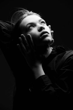 Siyah gömlekli, uzun kahverengi saçlı güzel bir kızın, umutla sakince yukarı baktığı bir fotoğraf. Güzellik, insanlar, duygular.