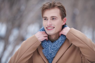 Bir kış günü, açık hava yürüyüşü sırasında neşeyle gülümseyen şık, şık ve genç bir adamın portresi. Erkek güzelliği ve modası. 