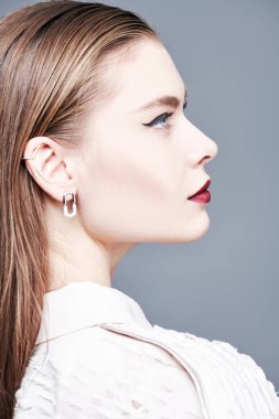 Güzel bir kadın model, şık bir özel tasarım bluz ve yüzünde parlak bir makyajla profilde poz veriyor. Makyaj ve saç stili. Yan manzara portresi. Yüksek moda çekim. 