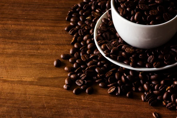 Roasted coffee beans in white cup on wooden background — Stock Photo, Image