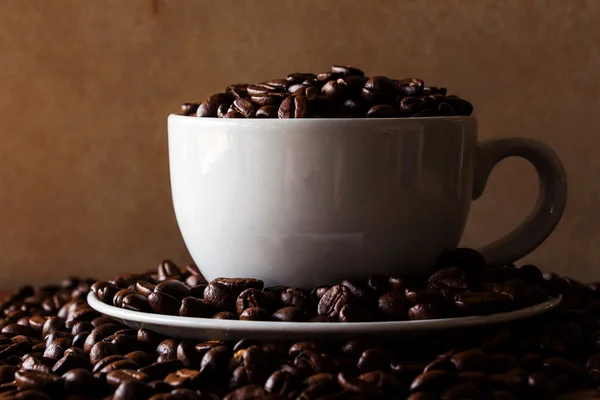 Roasted coffee beans in white cup on wooden background — Stock Photo, Image