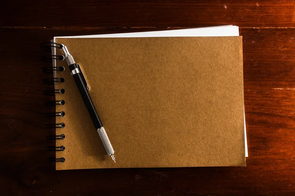 Старая винтажная записная книжка с ручкой на деревянном столе — стоковое фото