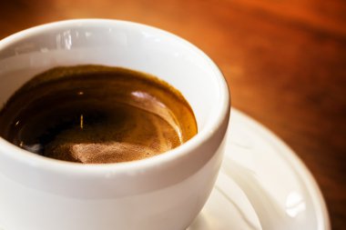 Tahta arka planda beyaz bir fincan kahve.